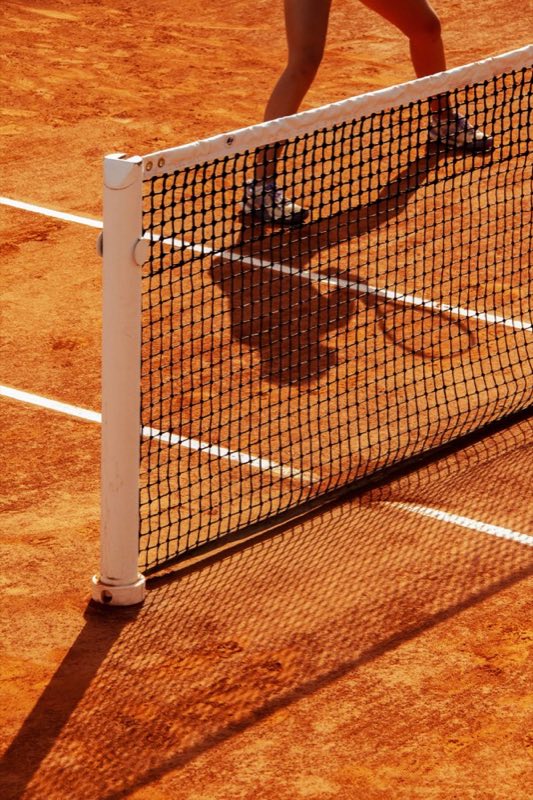 Tennis balls resting against the net on a clay court